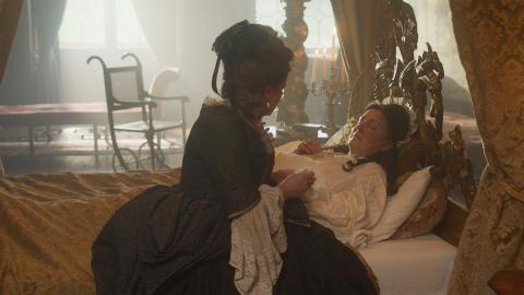 An actor portraying Queen Anne being comforted in bed
